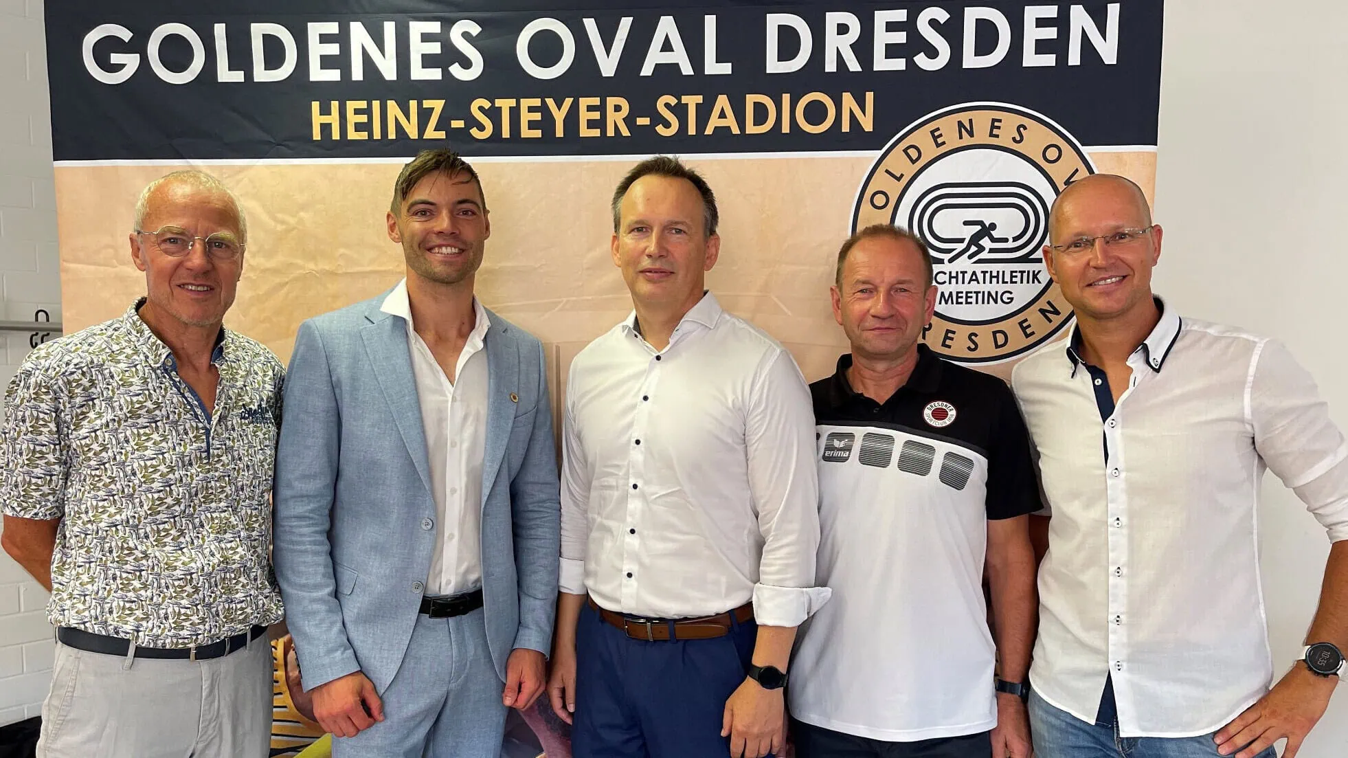 Das Bild zeigt eine Gruppe von Personen, die vor einem Banner mit der Aufschrift „Goldenes Oval Dresden“ stehen.